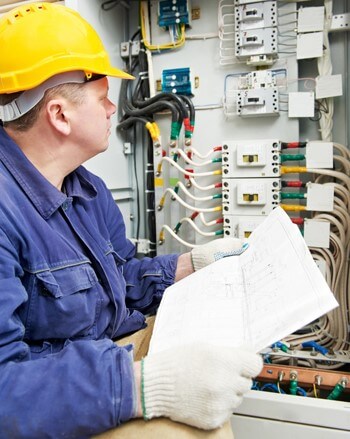 Electrician looking at an electrical control panel 